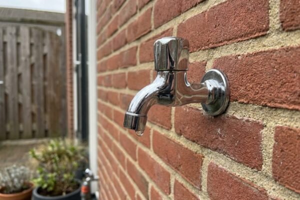 Een nieuw geplaatste vorstvrije buitenkraan aan de bakstenen gevel